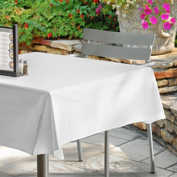 A white table with a Choice white vinyl table cover on it and a menu.