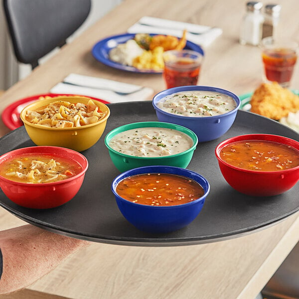 A tray with four Acopa Foundations melamine nappie bowls of assorted colors filled with soup on a table.