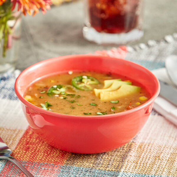 An Acopa orange melamine nappie bowl filled with soup and topped with jalapenos and avocado.