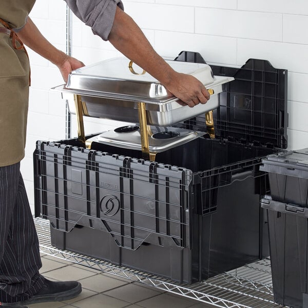 A person holding a black Lavex industrial storage tote filled with food.