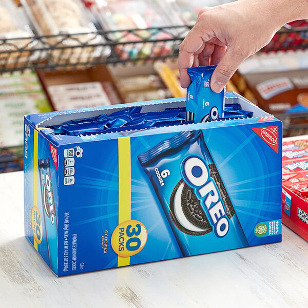 A hand putting a blue Nabisco Oreo cookie package into a box.