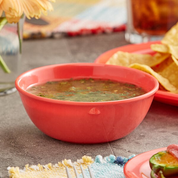 An Acopa orange melamine nappie bowl of soup and tortilla chips on a table.