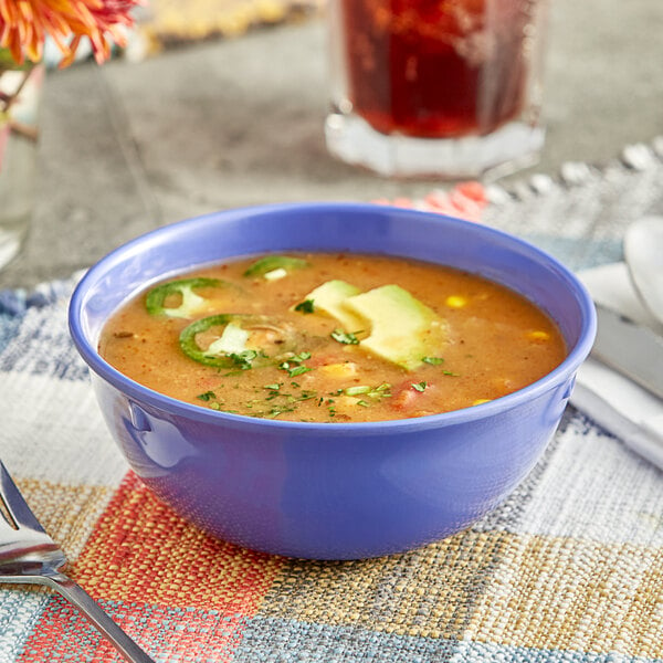 A purple Acopa melamine bowl filled with soup on a table.