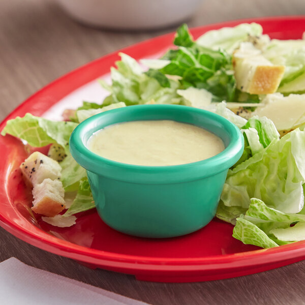 A plate of salad with Acopa Foundations green ramekin of sauce.