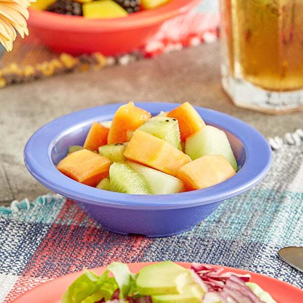 A table with Acopa Foundations purple melamine fruit dishes filled with fruit salad.