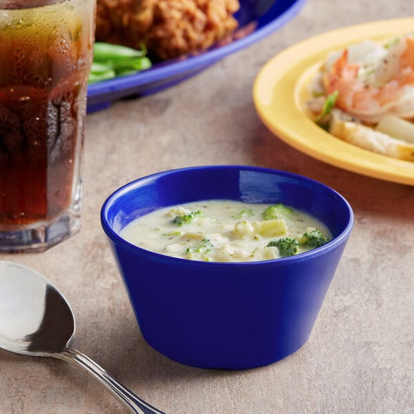 a blue bowl of soup next to a plate of food