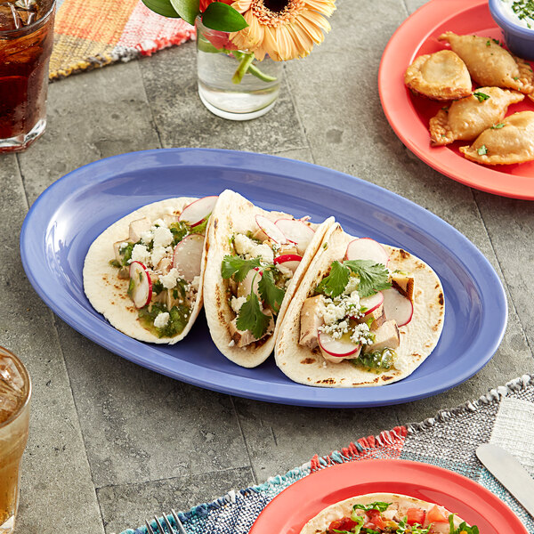 An Acopa purple narrow rim melamine oval platter with tacos and food on a table.