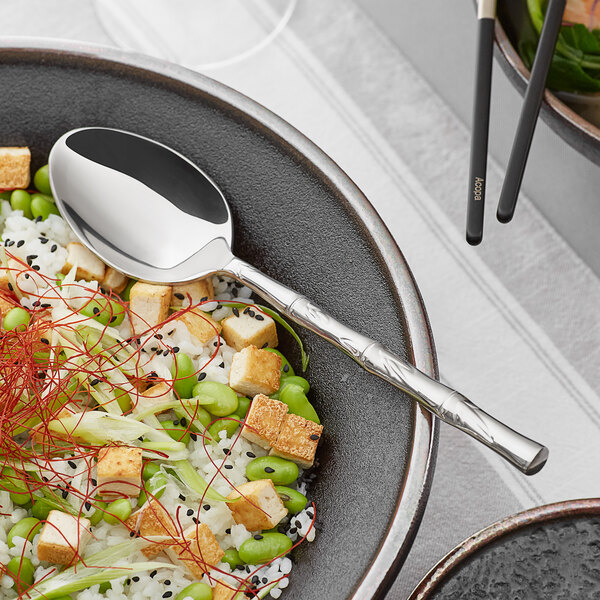 An Acopa stainless steel serving spoon in a bowl of food.