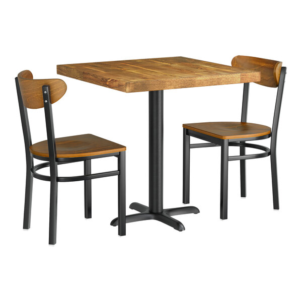 A Lancaster Table & Seating wood table with a butcher block top and two chairs with a wooden seat and backrest.