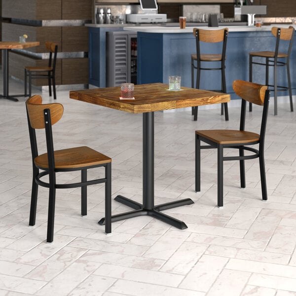 A Lancaster Table & Seating vintage butcher block table with two chairs in a restaurant dining area.