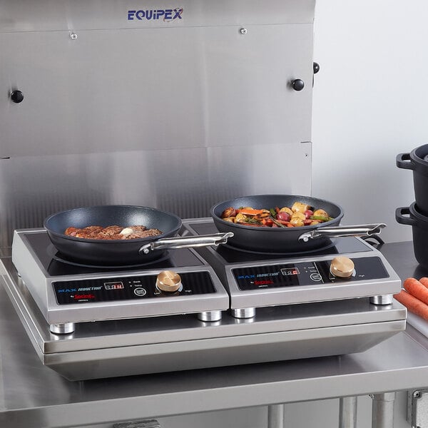 A dual-burner induction cooktop with digital controls and frying pans in use, designed for commercial kitchen settings.