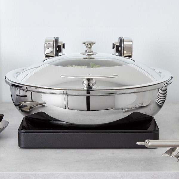 A Spring USA Slim-line induction warmer holding a silver pot with a lid on a counter.