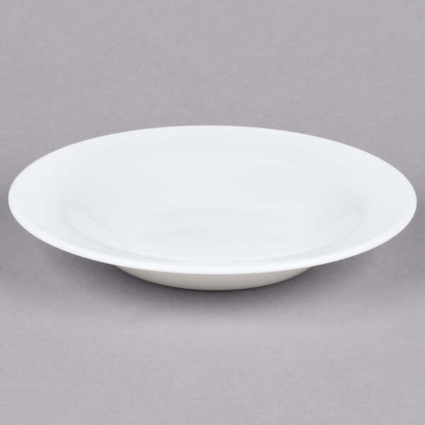 An Arcoroc white glass soup/pasta bowl on a gray surface.
