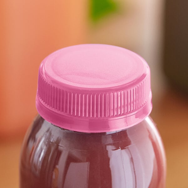 A bottle of juice with a pink tamper-evident cap on it.