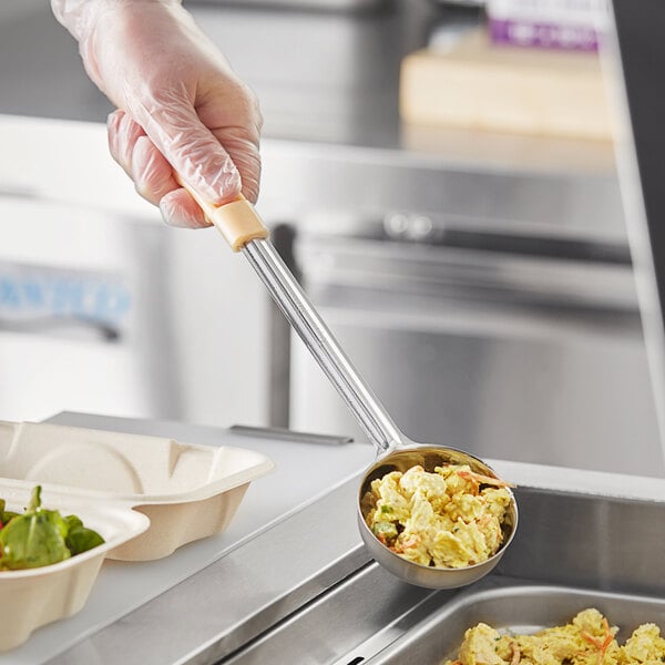 A hand holding a Choice ivory solid portion spoon with food in it.