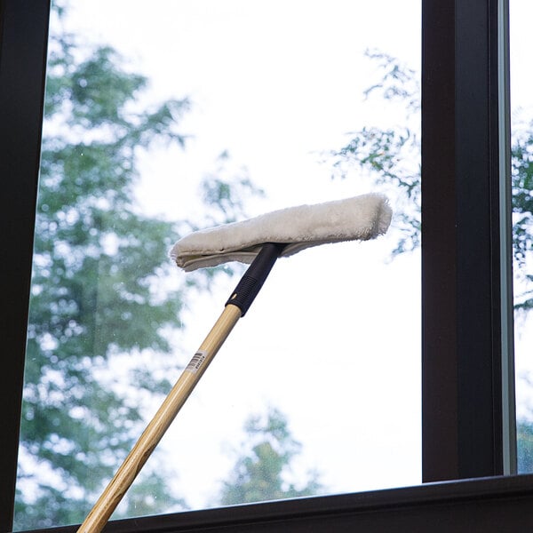 A Carlisle window cleaning tool with a plastic T-bar sitting on a window sill.