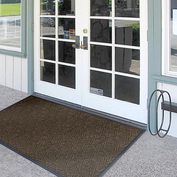 A brown Lavex Chevron Rib entrance mat with double glass doors.