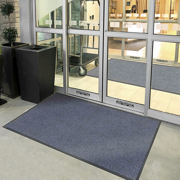 A blue Lavex Plush Dilour indoor entrance mat outside of a building.