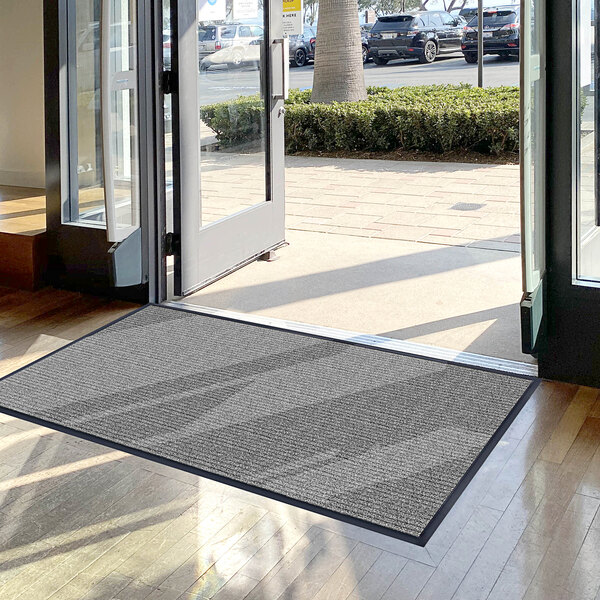 A Lavex grey indoor entrance mat with a large glass door.