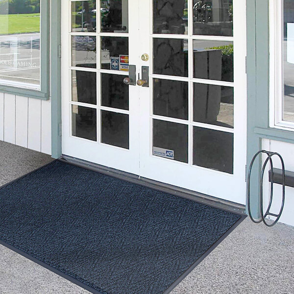 A black Lavex Chevron Rib entrance mat in front of double doors with glass panes.