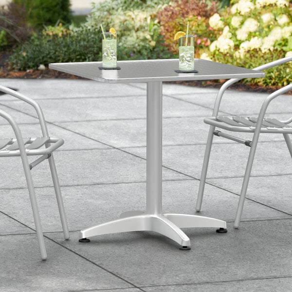 A Lancaster Table & Seating chrome square outdoor table with two glasses on it.