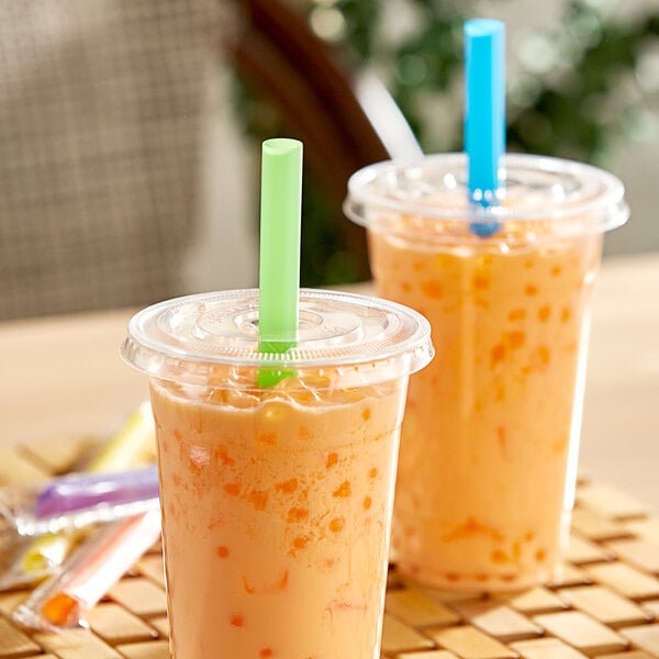 Two plastic cups with Choice neon wrapped straws filled with orange liquid.