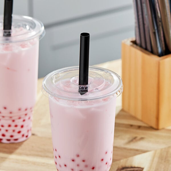 Two pink drinks in a wooden box with a black straw.