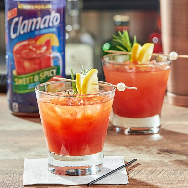 A Clamato Sweet & Spicy Michelada cocktail in a glass with a lemon slice and straw.