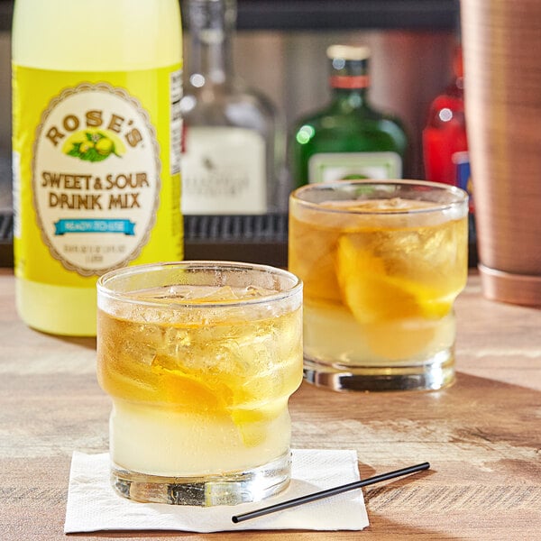 A glass of Rose's sweet and sour mix with ice and lemon slices.