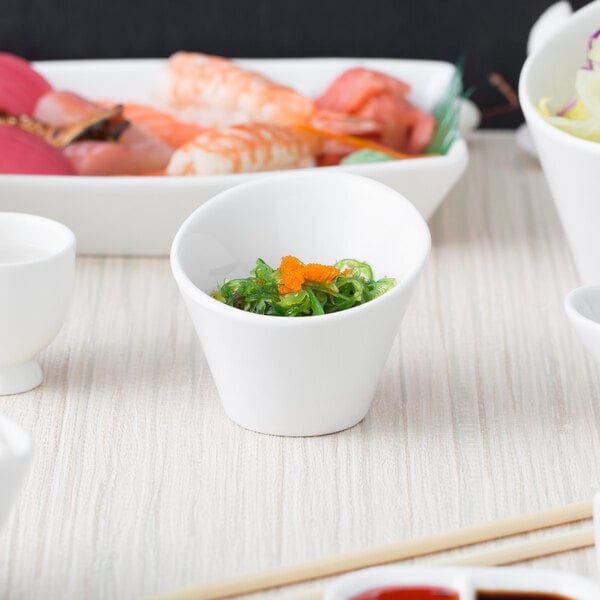 A close up of 10 Strawberry Street Whittier white porcelain tall slant bowl filled with food on a table.