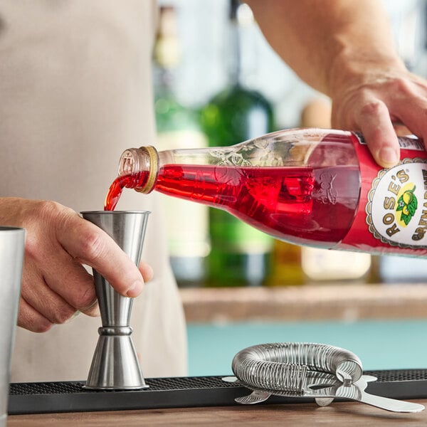 A bartender pouring Rose's grenadine into a glass.