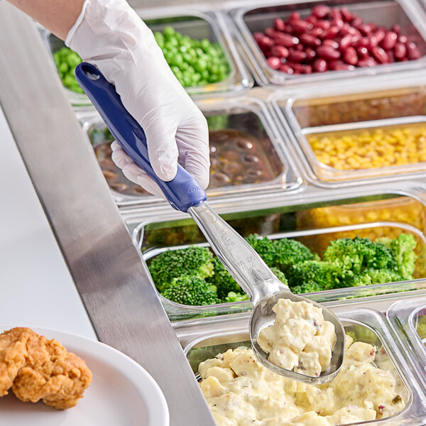 A person using a Vollrath blue oval portion spoon to serve food from a container.