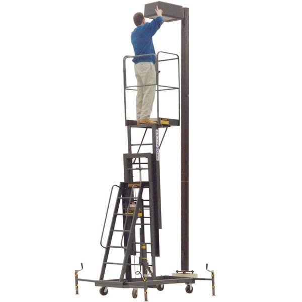 A man in a blue shirt standing on a Ballymore maintenance lift platform with guard rails.