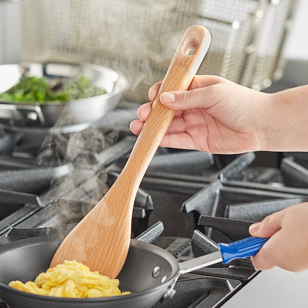 A wooden spatula stirring eggs
