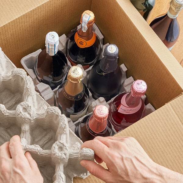 A hand using white material to open a Lavex wine shipper box containing bottles of wine.