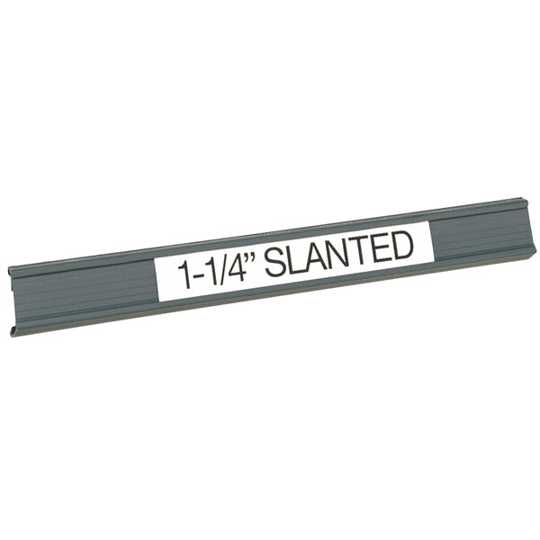 A gray slanted plastic label holder on a metal shelf with a white label.