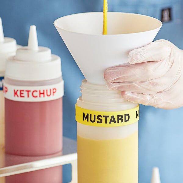 A hand putting a white silicone band labeled "Mustard" around a squeeze bottle of mustard.