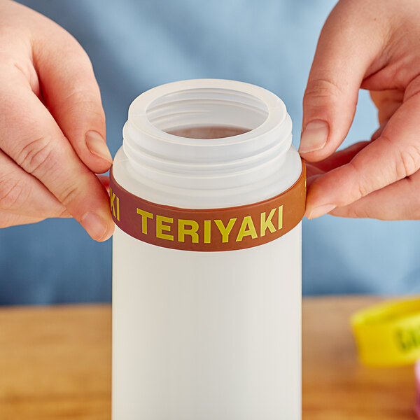 A person's hand squeezing a silicone label band onto a plastic bottle.