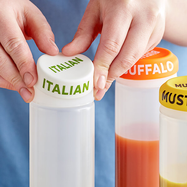 A hand using a white silicone lid to cover a plastic bottle filled with different colored liquids.
