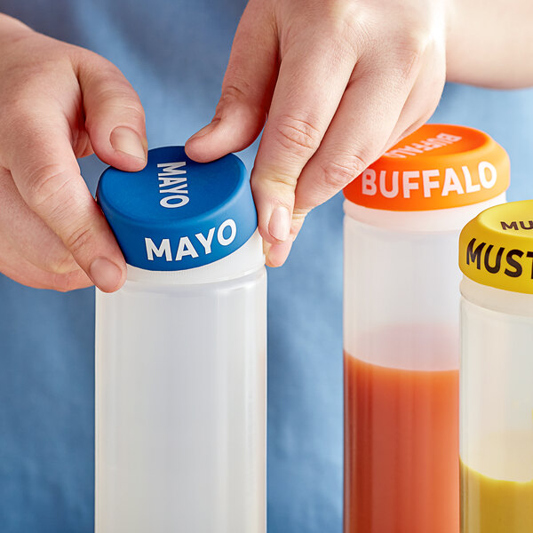A hand holding a plastic bottle with a silicone lid filled with different colored liquids.