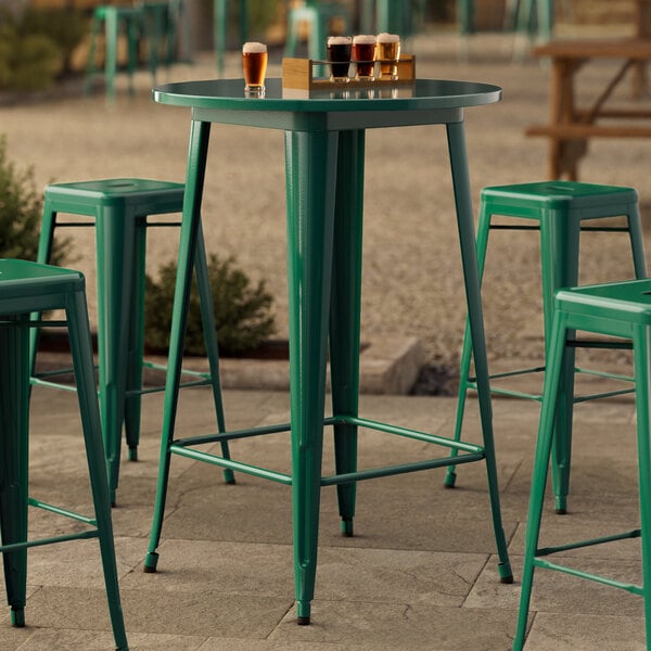 A Lancaster Table & Seating emerald green bar height table with green stool legs.