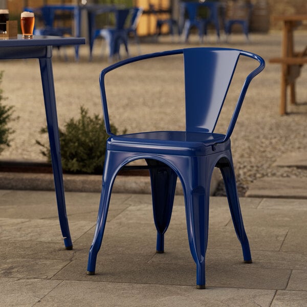 A blue Lancaster Table & Seating outdoor arm chair on a stone patio.