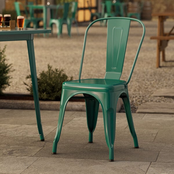 A green Lancaster Table & Seating outdoor cafe chair on a stone patio.