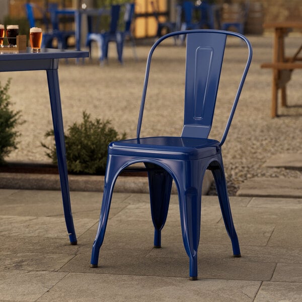 A blue Lancaster Table & Seating outdoor cafe chair on a stone patio.