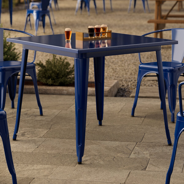 A Lancaster Table & Seating blue metal table with chairs on a patio.