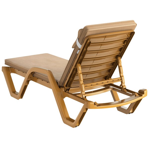 A tan Lancaster Table & Seating resin chaise lounge with beige cushion and pillow.