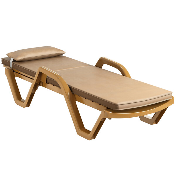 A Lancaster Table & Seating sand resin chaise lounge with a beige cushion and pillow.