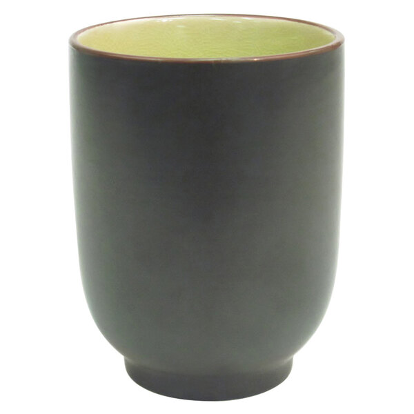 A black stoneware cup with a golden green rim.
