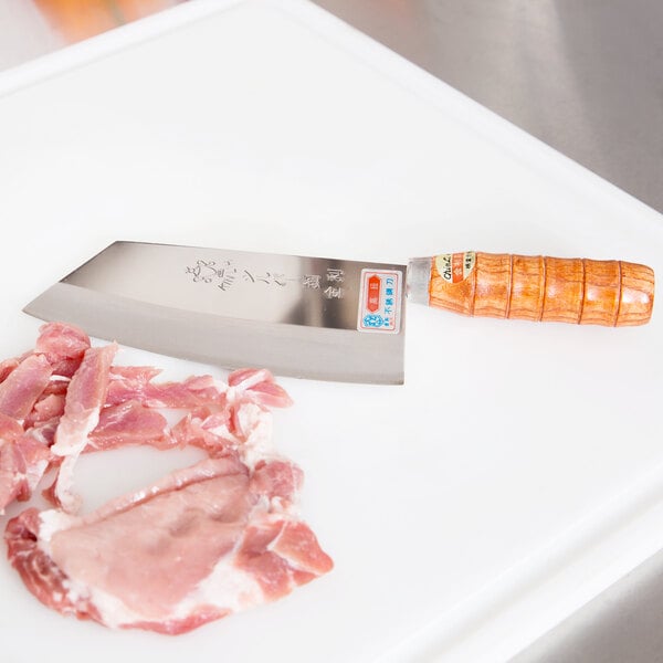 A Thunder Group stainless steel cleaver next to meat on a cutting board.