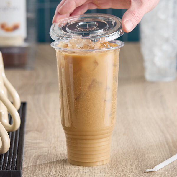 A clear 32 oz. plastic cold cup with a flat lid, filled with iced coffee.